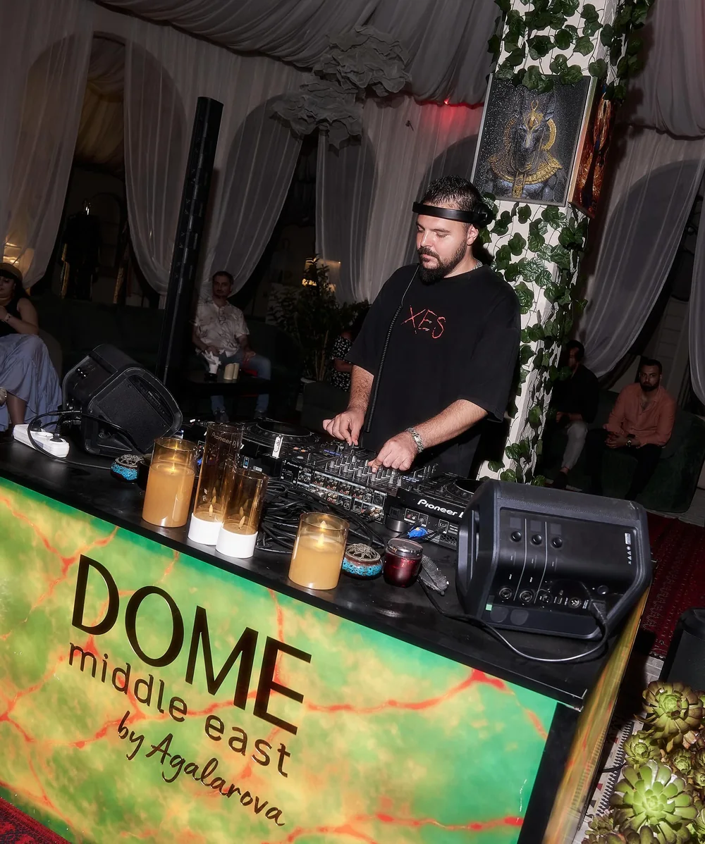 Диджей за стойкой с логотипом DOME, зелень и свечи